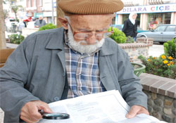 95 lik dede gazetesini büyüteçle okuyor